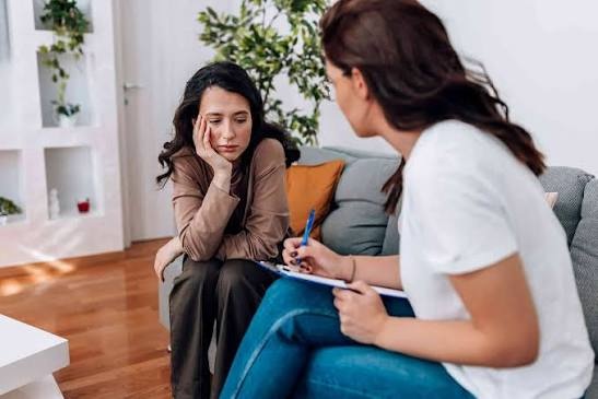 A therapist taking notes while listening to a client